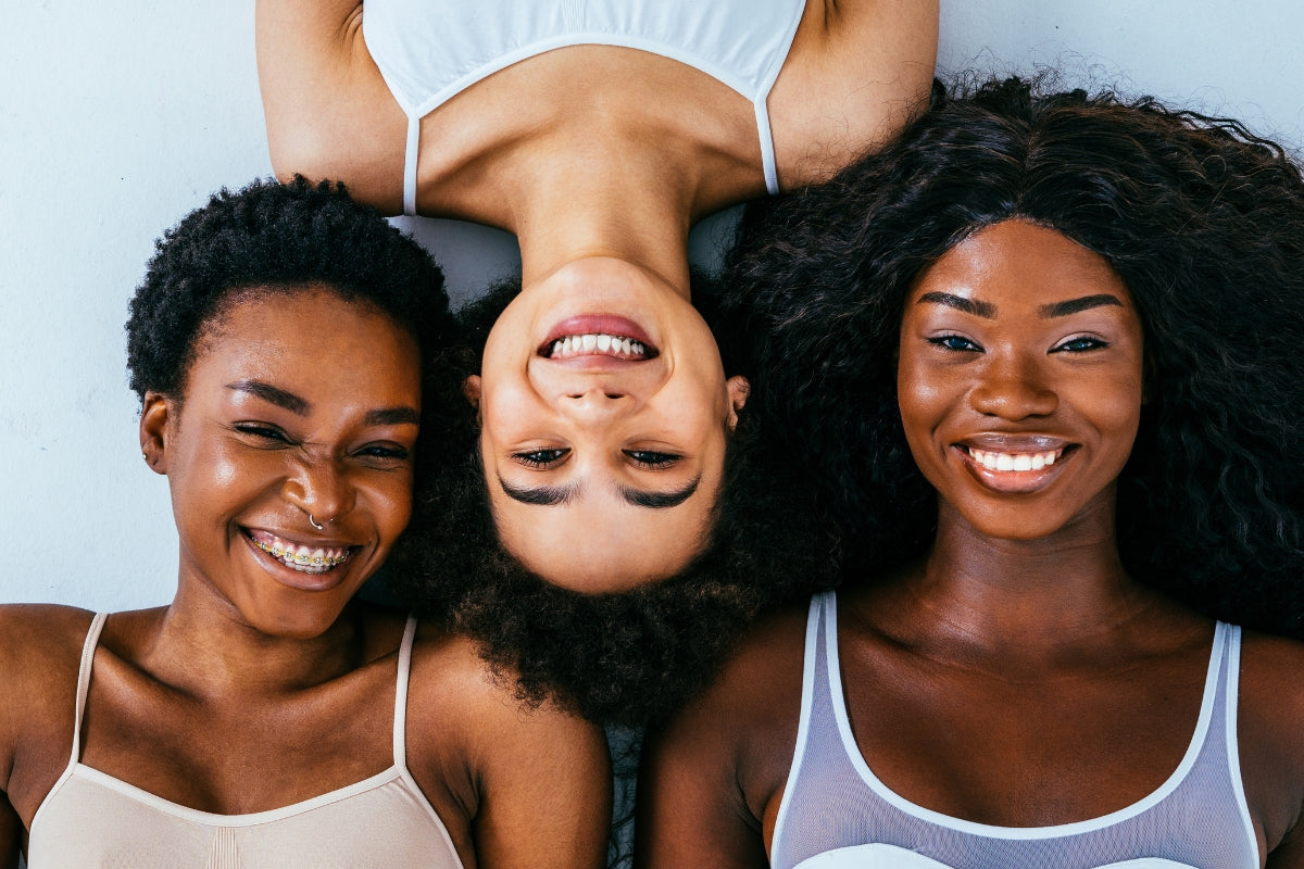 three women with different skin tone types, smiling